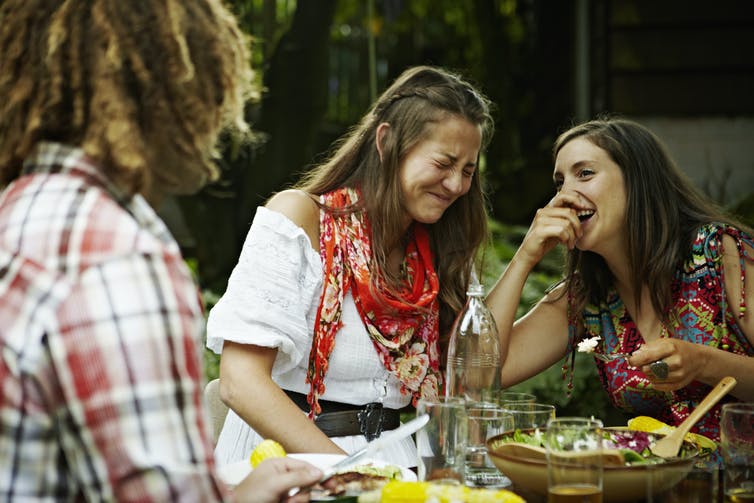 Des femmes riant ensemble lors d’un repas en plein air.